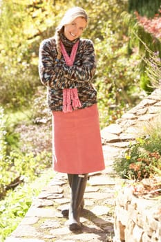 Full Length Portrait Of Young Woman Walking In Autumn Garden