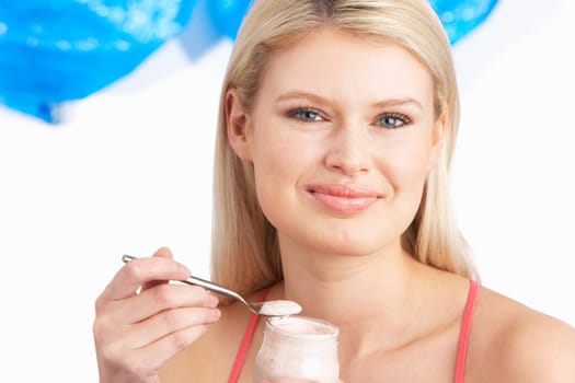 Young Woman Eating Yoghurt In Studio
