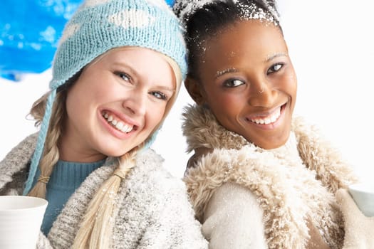 Two Young Women Wearing Warm Winter Clothes Holding Snowball In Studio