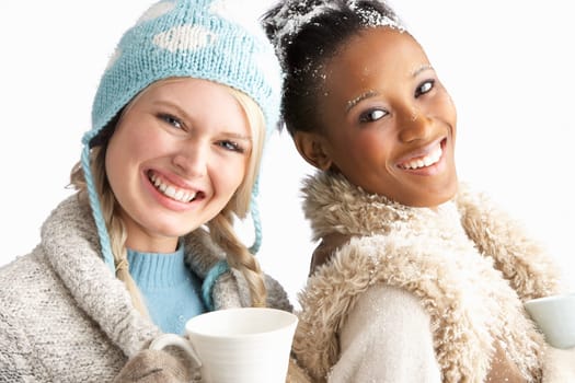 Two Young Women Wearing Warm Winter Clothes Holding Snowball In Studio