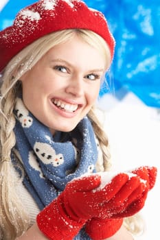 Young Woman Wearing Warm Winter Clothes And Hat Holding Snow In Studio