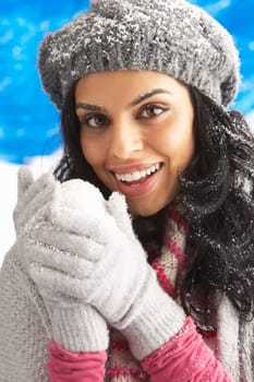 Young Woman Wearing Warm Winter Clothes And Hat Holding Snowball In Studio