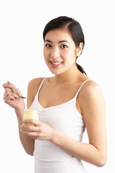 Young Woman Eating Yoghurt In Studio