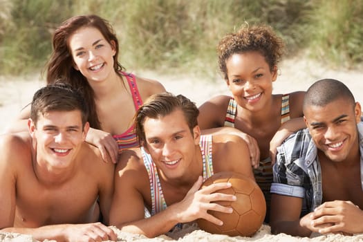 Group Of Friends Relaxing On Beach With Football Together