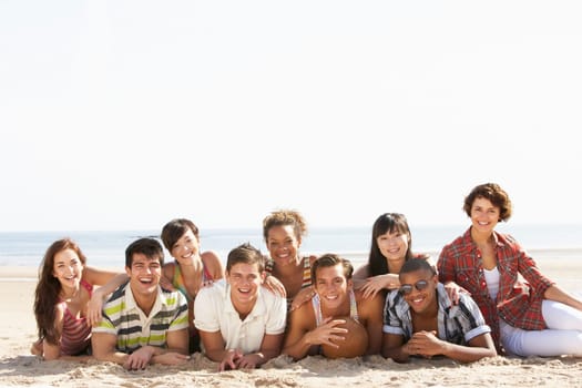 Group Of Friends Sitting On Beach Together
