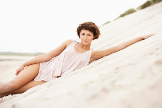 Fashionably Dressed Attractive Young Woman Laying Amongst Sand Dunes