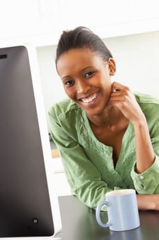 Young Woman Using Computer In Modern Kitchen