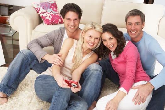 Group Of Friends Looking At Pictures On Digital Camera At Home
