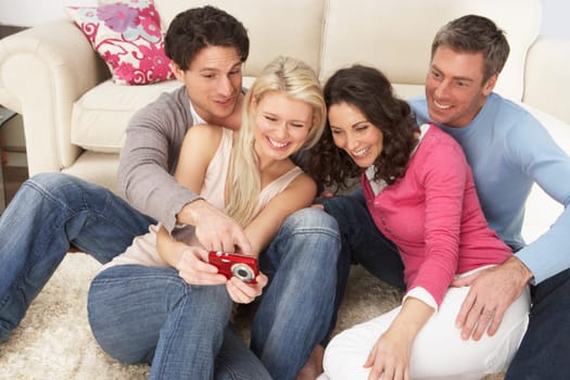 Group Of Friends Looking At Pictures On Digital Camera At Home