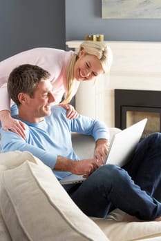 Couple Using Laptop Relaxing Sitting On Sofa At Home