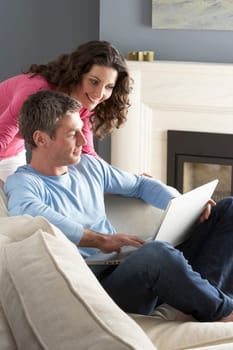 Couple Using Laptop Relaxing Sitting On Sofa At Home