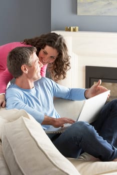 Couple Using Laptop Relaxing Sitting On Sofa At Home