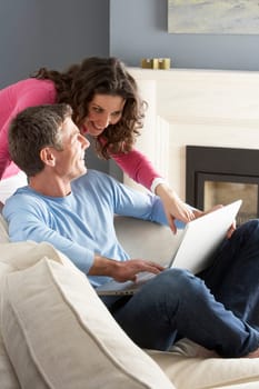 Couple Using Laptop Relaxing Sitting On Sofa At Home