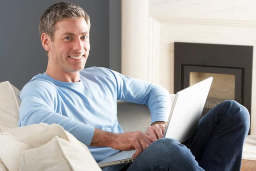 Man Using Laptop Relaxing Sitting On Sofa At Home