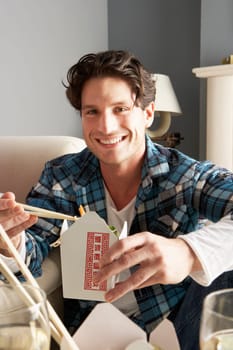 Young Man Relaxing Sitting On Sofa At Eating Chinese Meal At Home