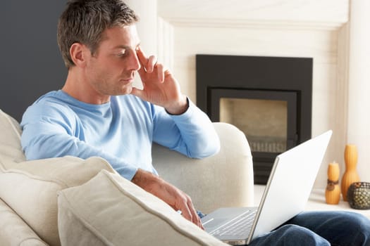 Man Using Laptop Relaxing Sitting On Sofa At Home