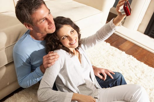 Couple Taking Photograph On Digital Camera At Home