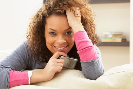 Woman Looking At Pictures On Digital Camera Relaxing Sitting On Sofa At Home