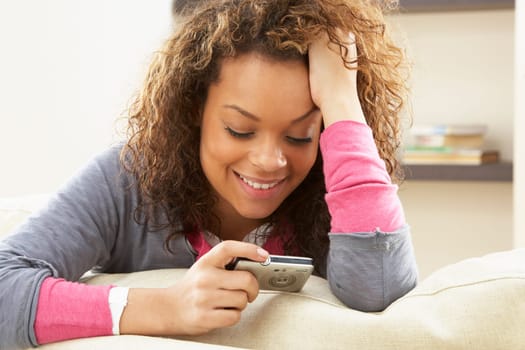 Woman Looking At Pictures On Digital Camera Relaxing Sitting On Sofa At Home