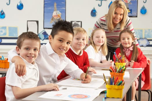 Group Of Primary Schoolchildren And Teacher Working At Desks In Classroom