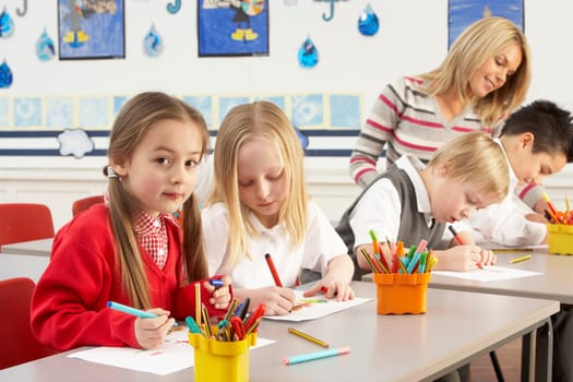 Group Of Primary Schoolchildren And Teacher Having lesson In Classroom