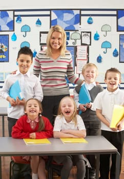 Portrait Of Group Of Primary Schoolchildren And Teacher Sitting At Desk In Classroom