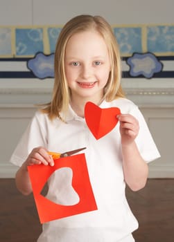 Female Primary School Pupil Cutting Out Paper Shapes In Craft Lesson