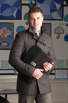 Portrait Of Male Primary School Teacher Standing In Classroom