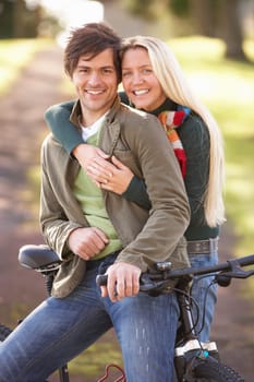 Portrait Of Young Couple With Cycle In Autumn Park