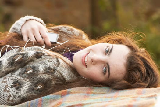 Portrait Of Beautiful Teenage Girl Outdoors Listening To MP3 Player In Autumn Landscape