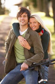Portrait Of Young Couple With Cycle In Autumn Park