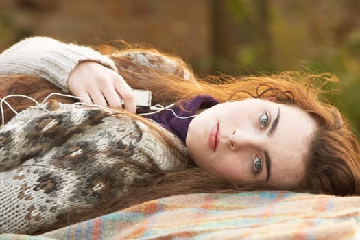 Portrait Of Beautiful Teenage Girl Outdoors Listening To MP3 Player In Autumn Landscape