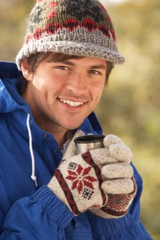 Young Man Relaxing With Thermos Flask In Autumn Landscape