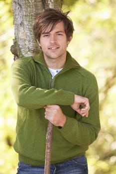 Young Man Outdoors Walking In Autumn Woodland Holding Walking Stick