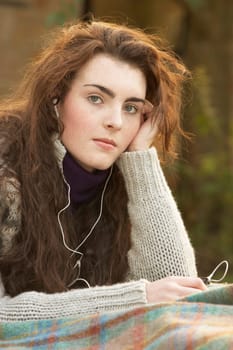 Portrait Of Beautiful Teenage Girl Outdoors Listening To MP3 Player In Autumn Landscape
