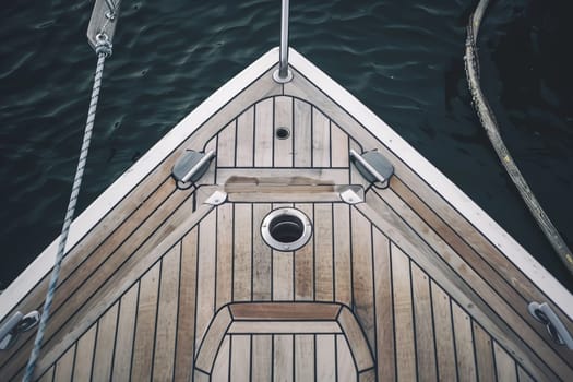 Wooden yacht deck with stainless steel fittings over calm water.