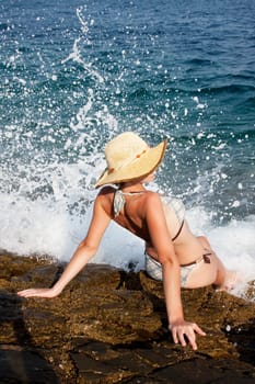 woman with hat sunbathing on rocks
