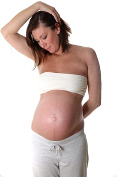 Young woman with pregnancy belly against white background looking at her belly