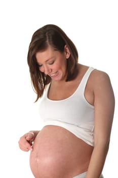 Pregnant woman pointing at her stomach - standing sideways - in front of white background