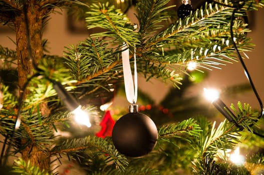 Christmas ball hanging from Christmas tee with lights