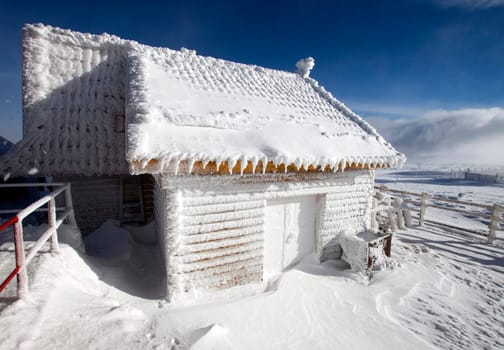 Wooden cottage covered with snow in the mountains