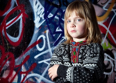 child in front of graffiti wall in urban area. Cool young boy by street art in deprived town area
