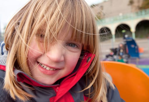 child in playground happy smiling. pretty blond boy with long hair full of joy. Childhood image of play