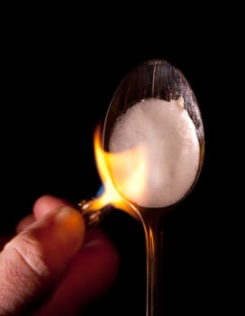 heroin or narcotic drug cook in spoon with lighter and flame. dangerous preparation of illegal substance