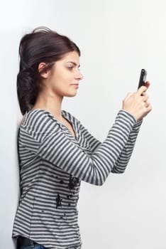 Pretty young brunette woman sending SMS from her cellphone
