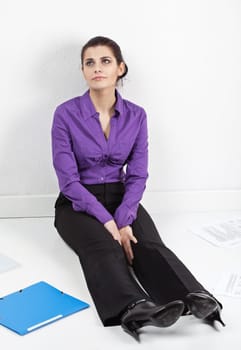 Young pretty secretary sitting on the floor with documents and folders scattered around