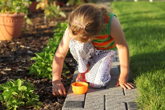 Small girl is helping in garden to weed up