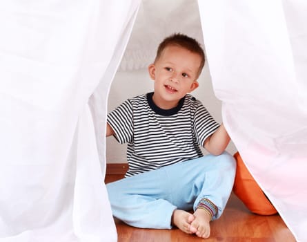 Adorable boy playing hide-and-seek at home