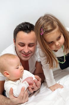 Young happy father playing with two children - a baby and a toddler