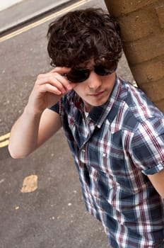 High angle street portrait of young man playing with his sun glasses